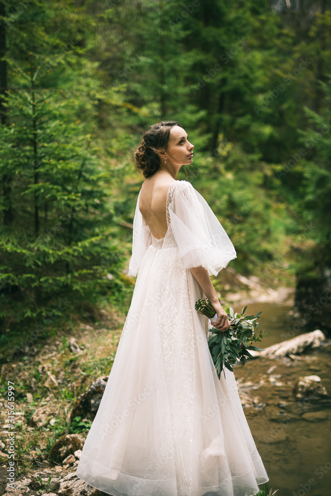 beautiful bride in white dress posing in nature