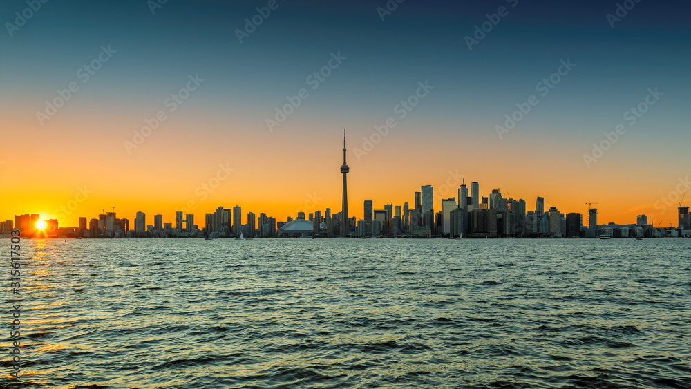 Toronto city skyline at sunset with CN Tower over Ontario Lake, Canada