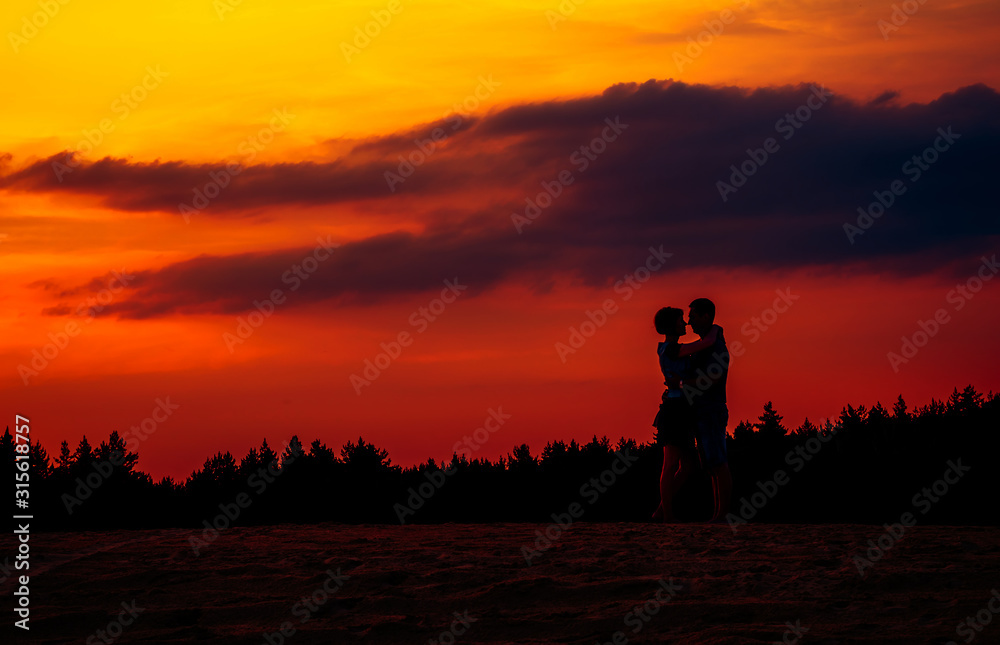 Girl and guy holding hands and sit on the shore of a forest lake. beautiful view of the lake . back view.