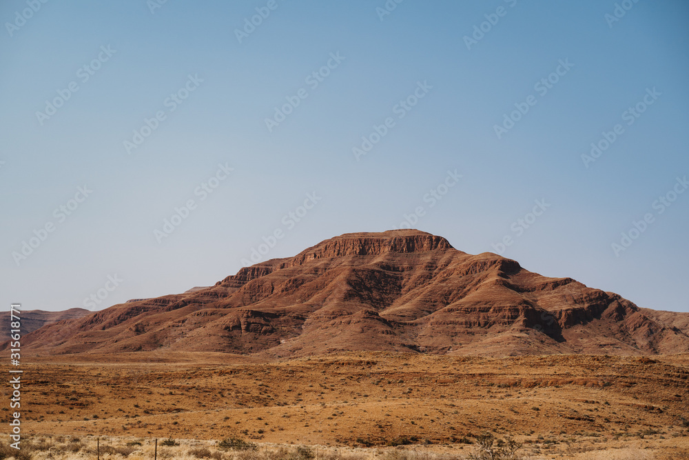 imposing red mountains and bald granite peak with blue sky