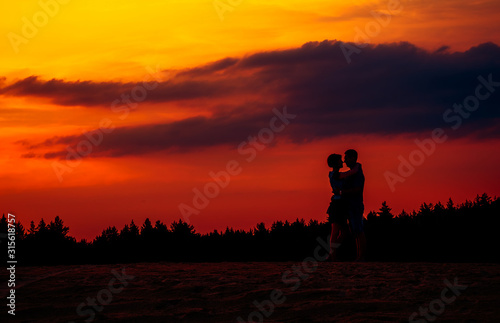 Girl and guy holding hands and sit on the shore of a forest lake. beautiful view of the lake . back view.