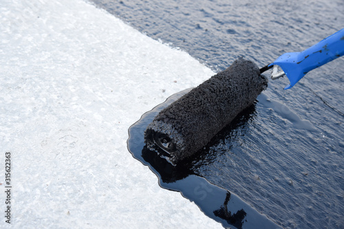 Foto Worker applies bitumen mastic on the foundation