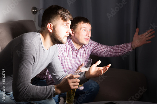 Worried men watching match at home