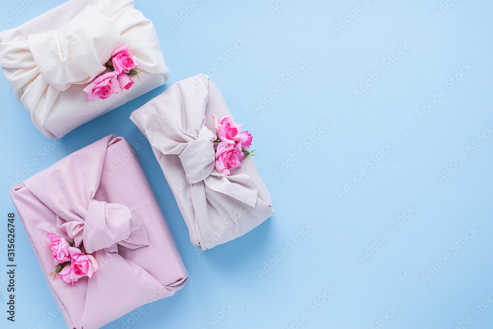 Holiday gift wrapped fabric in the manner of Furoshiki on a fashionable blue background. Concept Zero Waste Life.
