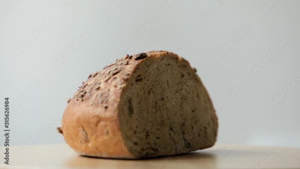 Close up shot of rustic bread rotating on the wooden board with white background
