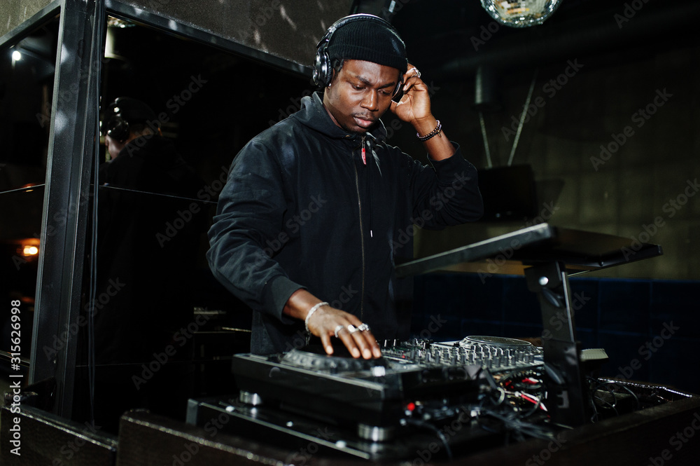 African american dj play music on decks at night club. African american dj play music on decks at night club.