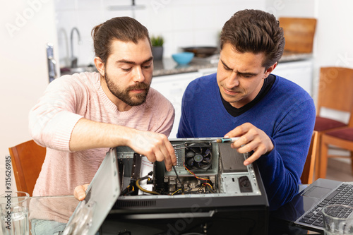 Two men are engaged in assembling a desktop computer