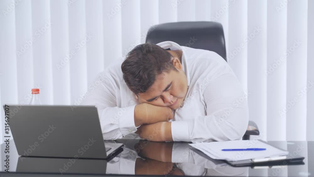 Overweight businessman sleeping on desk in the office room with a laptop on the table. Shot in 4k resolution Overweight businessman sleeping on desk in the office room with a laptop on the table. Shot in 4k resolution