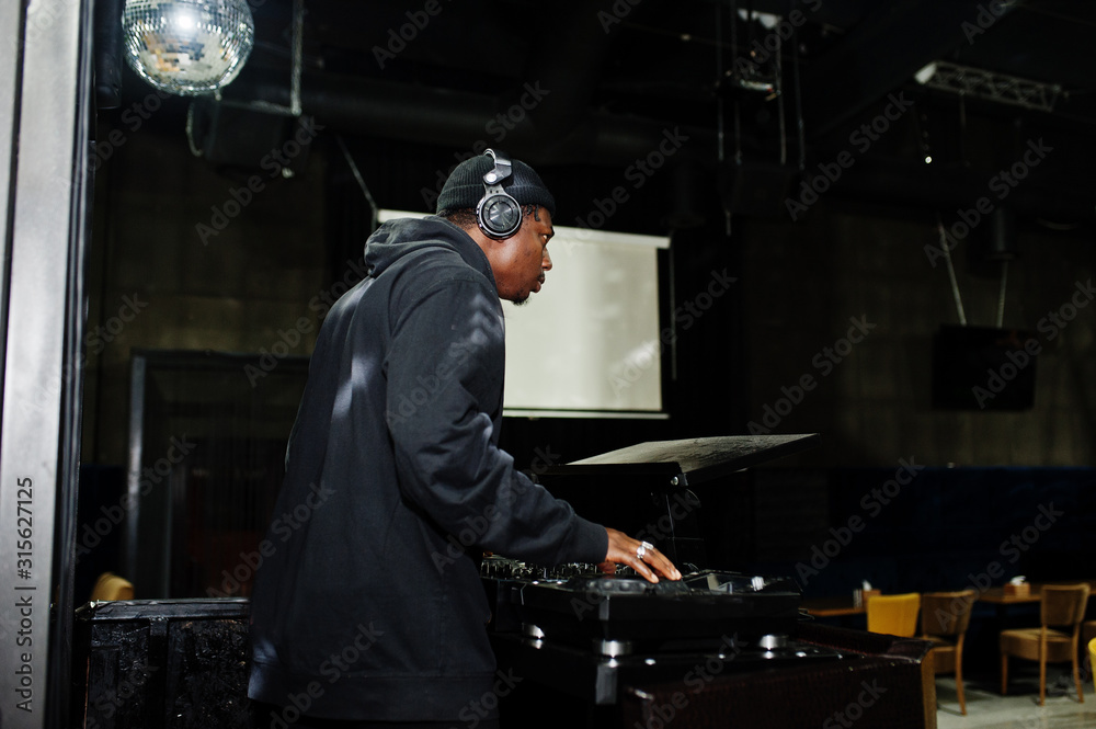 African american dj play music on decks at night club. African american dj play music on decks at night club.