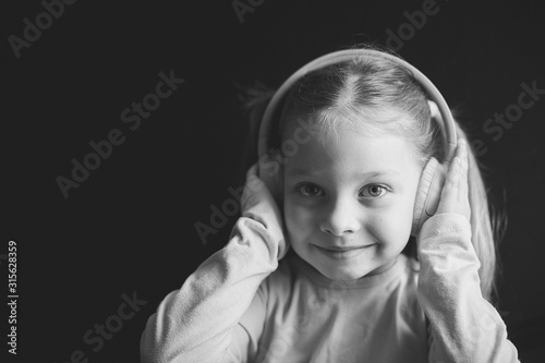 little girl in headphones listening to music, black and white portrait of a Caucasian child