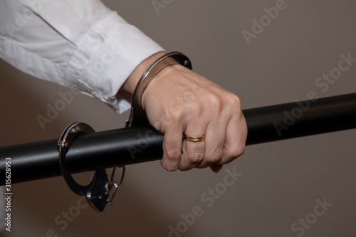 Close-up. Arrested woman handcuffed hands at the back isolated on gray background