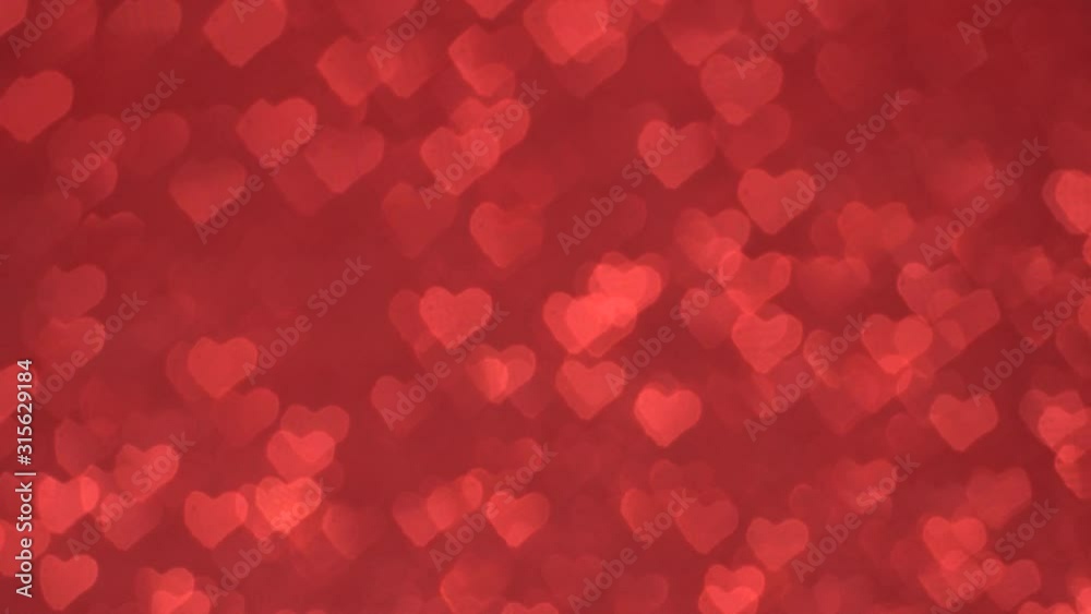 Many heart-shaped bokeh move cyclically against a red background. Many heart-shaped bokeh move cyclically against a red background.