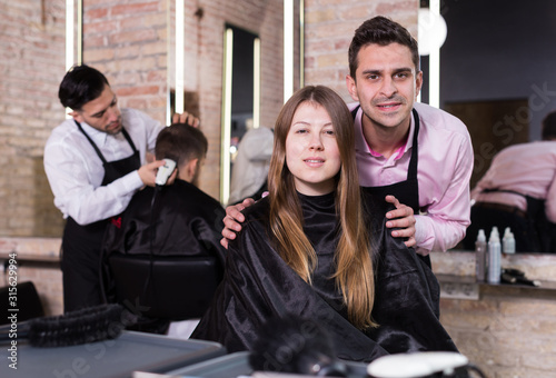 Hairdresser discussing female customer preferences in barbershop