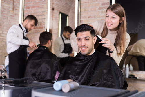 Hairdresser doing styling of guy with electric hair clipper