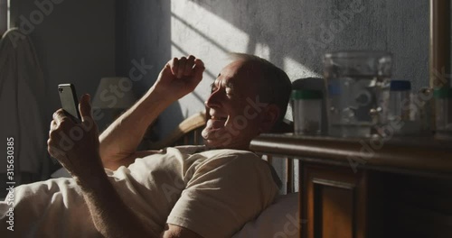 Senior man using digital tablet on bed photo