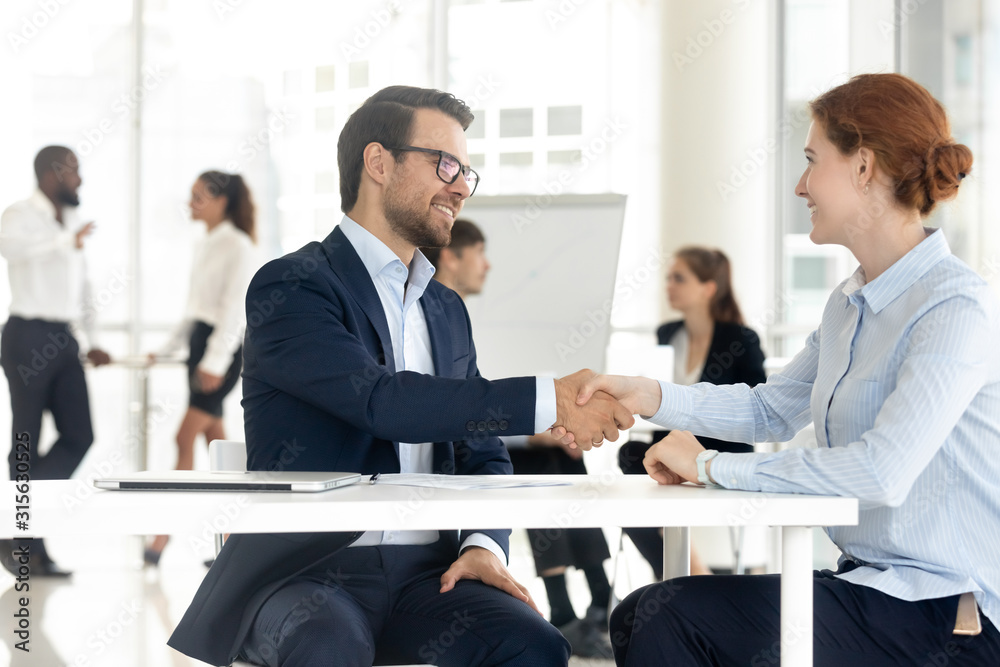 Smiling diverse business partners handshake closing deal at meeting Smiling diverse business partners handshake closing deal at meeting