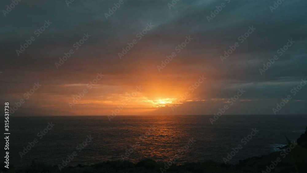 Extensive wide view of the beautiful sunset of the orange sun over the ocean in autumn. The rays of the sun fall on the sea, hiding behind large clouds. The beauty of nature from a bird's flight. Extensive wide view of the beautiful sunset of the orange sun over the ocean in autumn. The rays of the sun fall on the sea, hiding behind large clouds. The beauty of nature from a bird's flight.