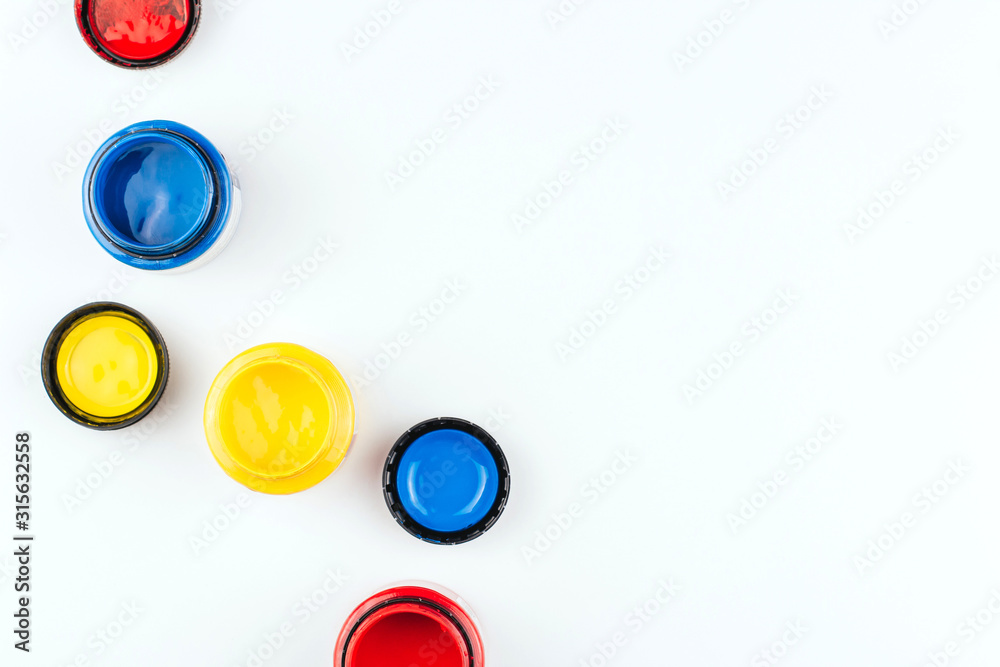 Cans of acrylic paint in blue, red and yellow on a white background copy space. Artistic paints.