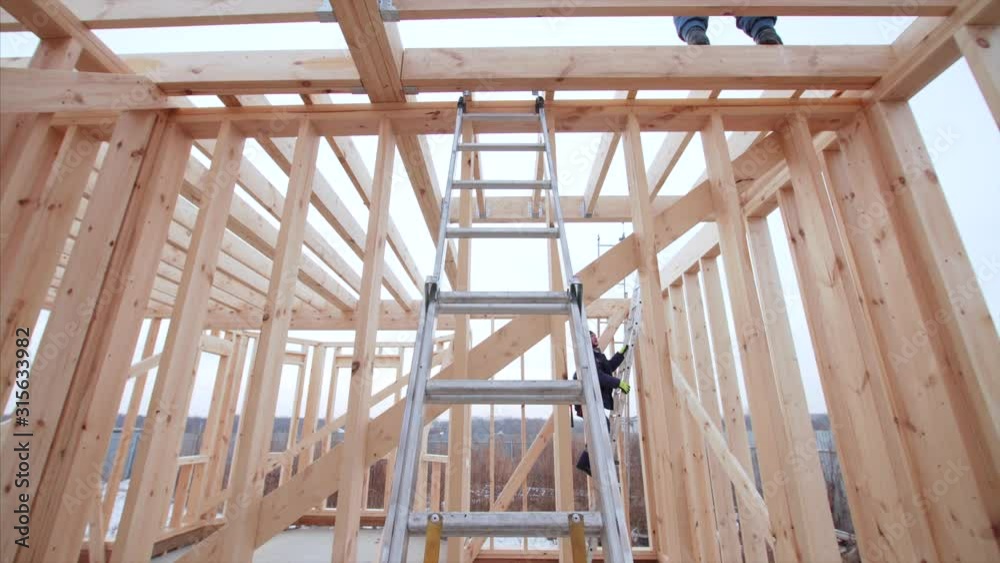 Zooming in view of steel ladder inside wooden frame house under construction. Winter Zooming in view of steel ladder inside wooden frame house under construction. Winter