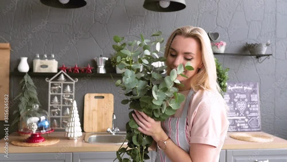 joyful woman makes a bouquet for table setting. The blonde is making a bouquet of eucalyptus. Festive table setting. Florist soborset bouquet on the table joyful woman makes a bouquet for table setting. The blonde is making a bouquet of eucalyptus. Festive table setting. Florist soborset bouquet on the table