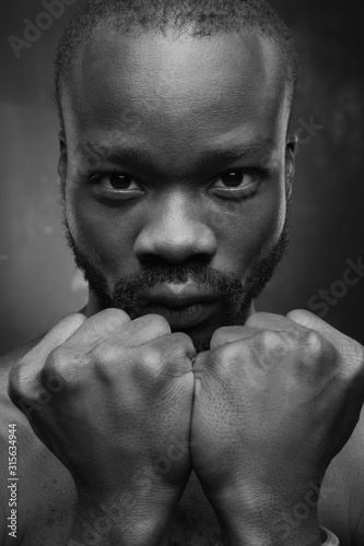 black and white portrait of a black handsome guy looking at the camera holding his fists