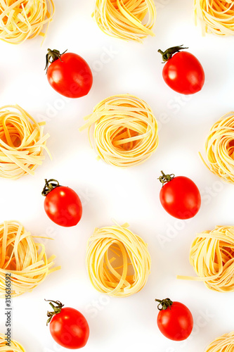 Raw italian pasta with tomatoes creative pattern on a white background top view.