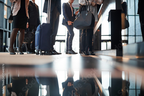 Close-up of people holding luggage and standing in a row at the airport