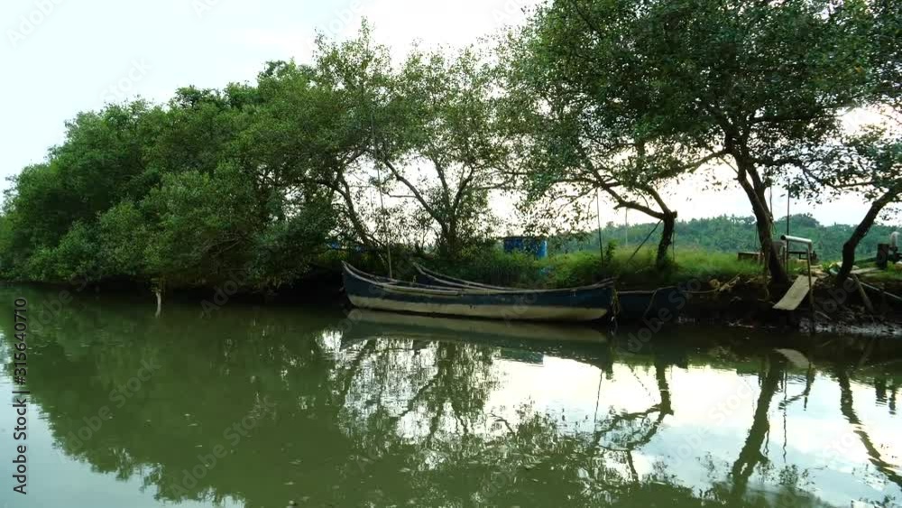Boat ride in a narrow river with boats parked on the bank, India Boat ride in a narrow river with boats parked on the bank, India