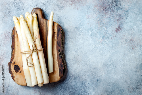 Bunch of raw white asparagus served on wooden board. Top view, copy space