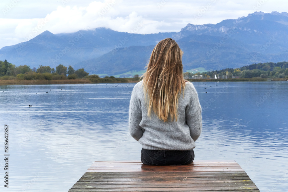 Fototapeta premium Woman in a jetty facing the lake