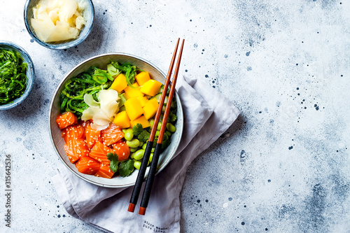 Hawaiian salmon poke bowl with seaweed, avocado, edamame, mango and pickled ginger. Top view, overhead, flat lay photo