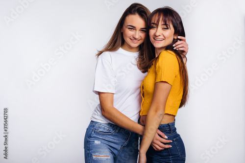 two girls in casual wear hugging and smiling. studio photo.