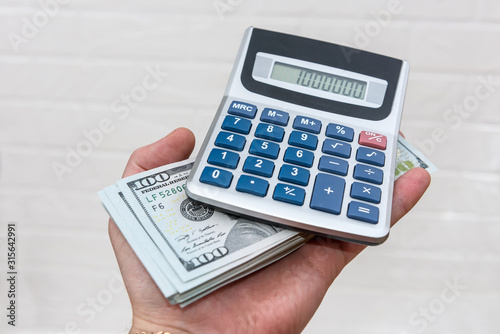 Hand holds dollars and calculator isolated on white background