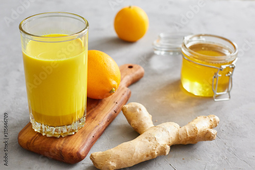 Health concept. Golden milk, ginger, lemon, honey on a grey concrete background. Health and energy boosting, flu remedy, natural cold fighting drink. Clean eating, detox, weight loss concept. photo