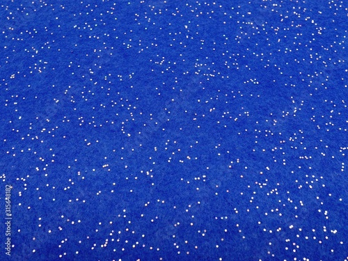 Bright blue photo background with felt fabric covered with small glittery sequins.