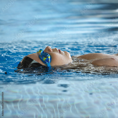 Swimming lesson. Child in the pool. Boy learns to swim