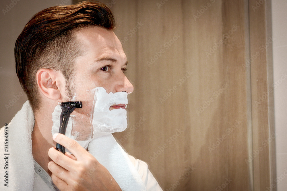 Man shaving with razor in the bathroom. Man shaving with razor in the bathroom.