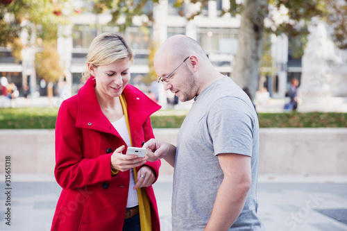 Couple of young people on smartphone searching for the right way in the city streets.