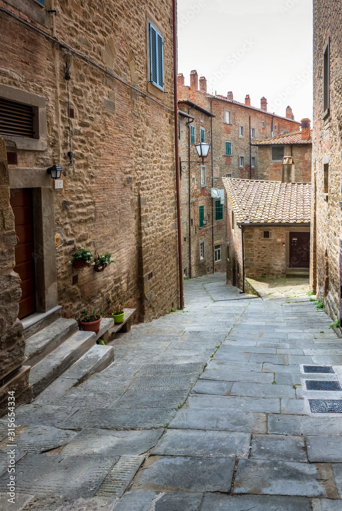 View with narrow picturesque medieval street of Tuscany old town Cortona, Italy
