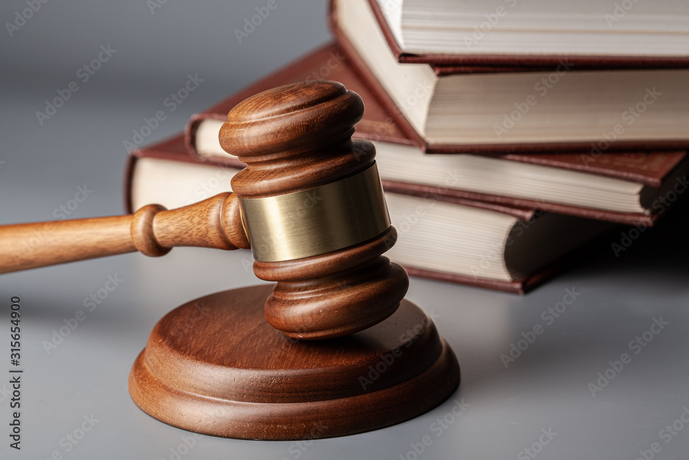 Brown wooden gavel with stack of books on gray table