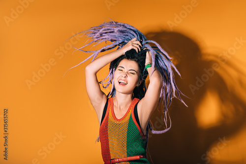 Canvas-taulu Woman with purple dreadlocks is dancing on an orange background