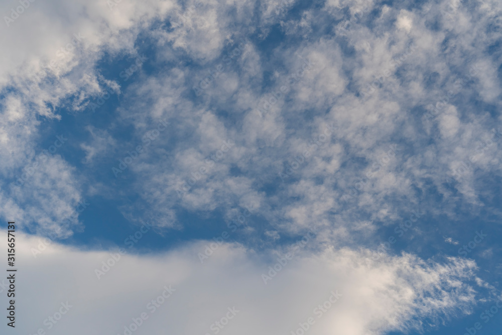 Naklejka premium Beautiful cirrus and cumulus clouds on a bright blue sky. Colorful positive natural landscape