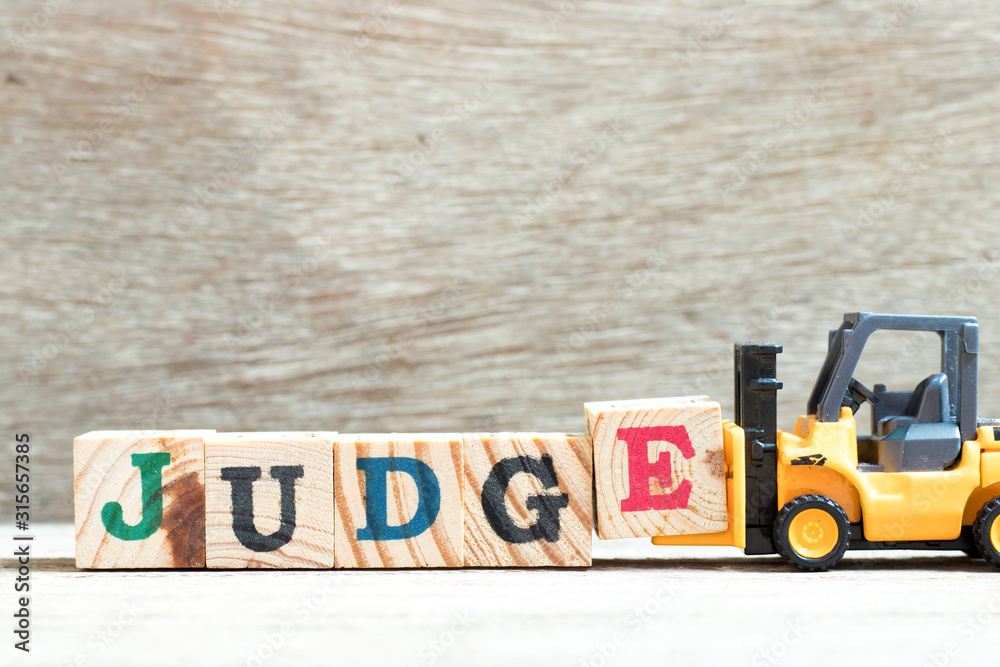 Fototapeta premium Toy forklift hold letter block e to complete word judge on wood background