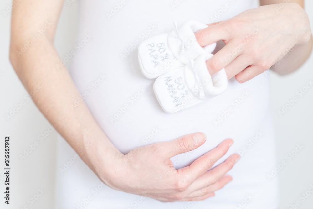 young pregnant woman with baby booties in hands - 50% Dad 50% Mum - Gender reveal young pregnant woman with baby booties in hands - 50% Dad 50% Mum - Gender reveal