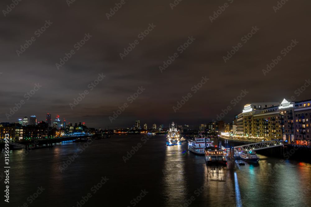Illuminated ship on a river Thames in the dark, London. A shot from Tower bridge.