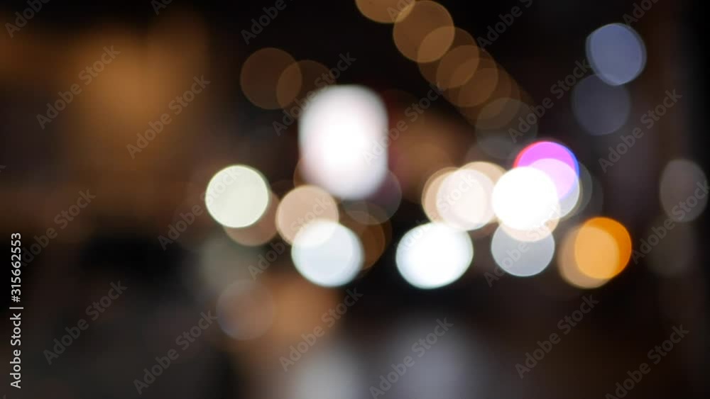 Beautiful glittering bokeh in dark blurry background at night. The round colorful bokeh shine from car lights in traffic jam on city street. Out of focus with blurry. Unfocused city lights. Traffic