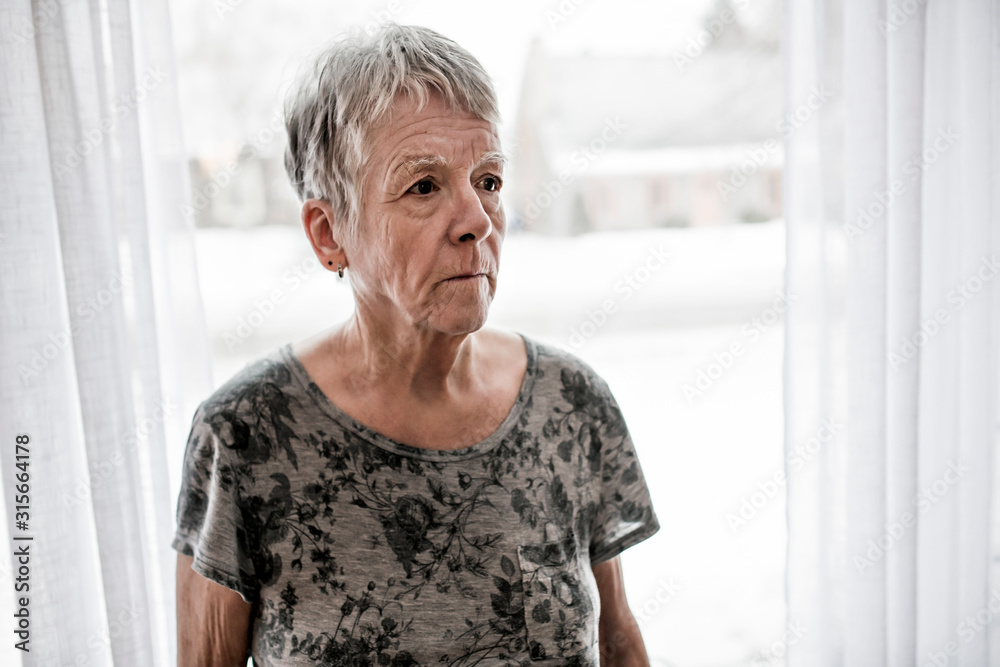 Sad senior woman at home close to window Sad senior woman at home close to window