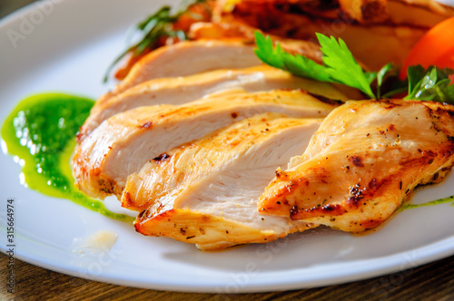 Grilled chicken breast with potato in a plate on wooden table photo