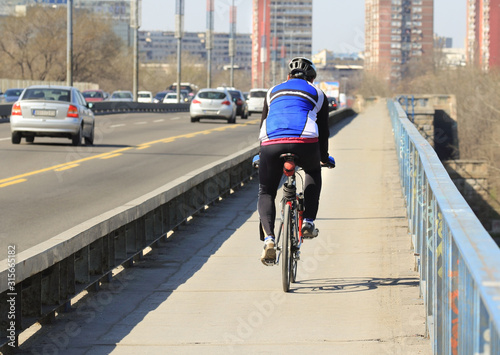 One driving bicycle over the Branko's bridge in Belgrade with the cars in the background. photo