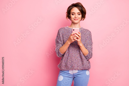 Portrait of her she nice attractive lovely pretty cute winsome focused confident cheerful brown-haired girl holding hands cell sending sms isolated over pink pastel color background